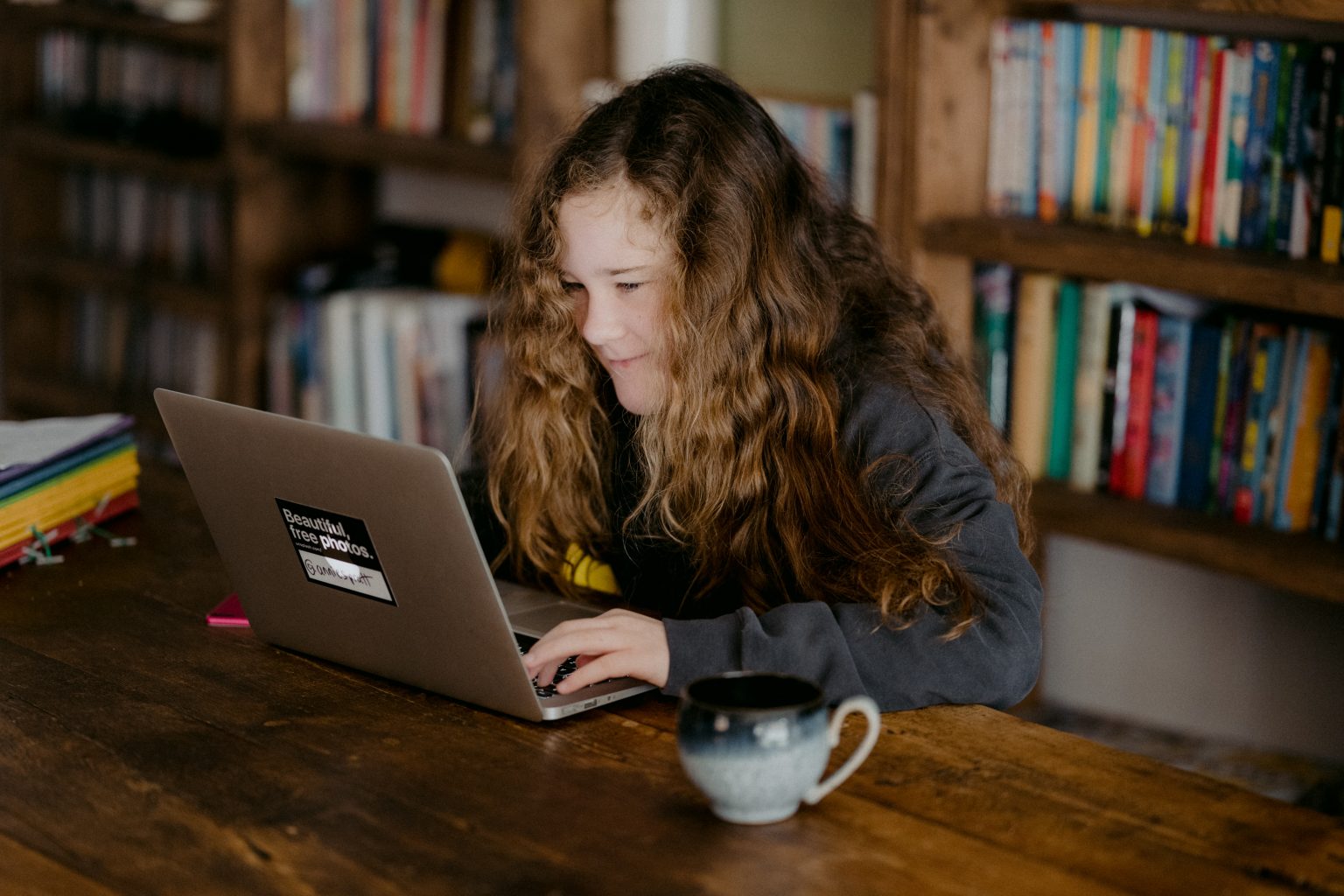 kid smiling at a computer in a library