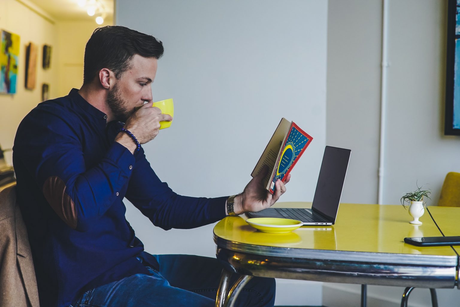 man reading a book and drinking coffee