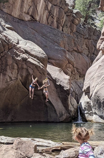 girls jumping off cliff into small lake