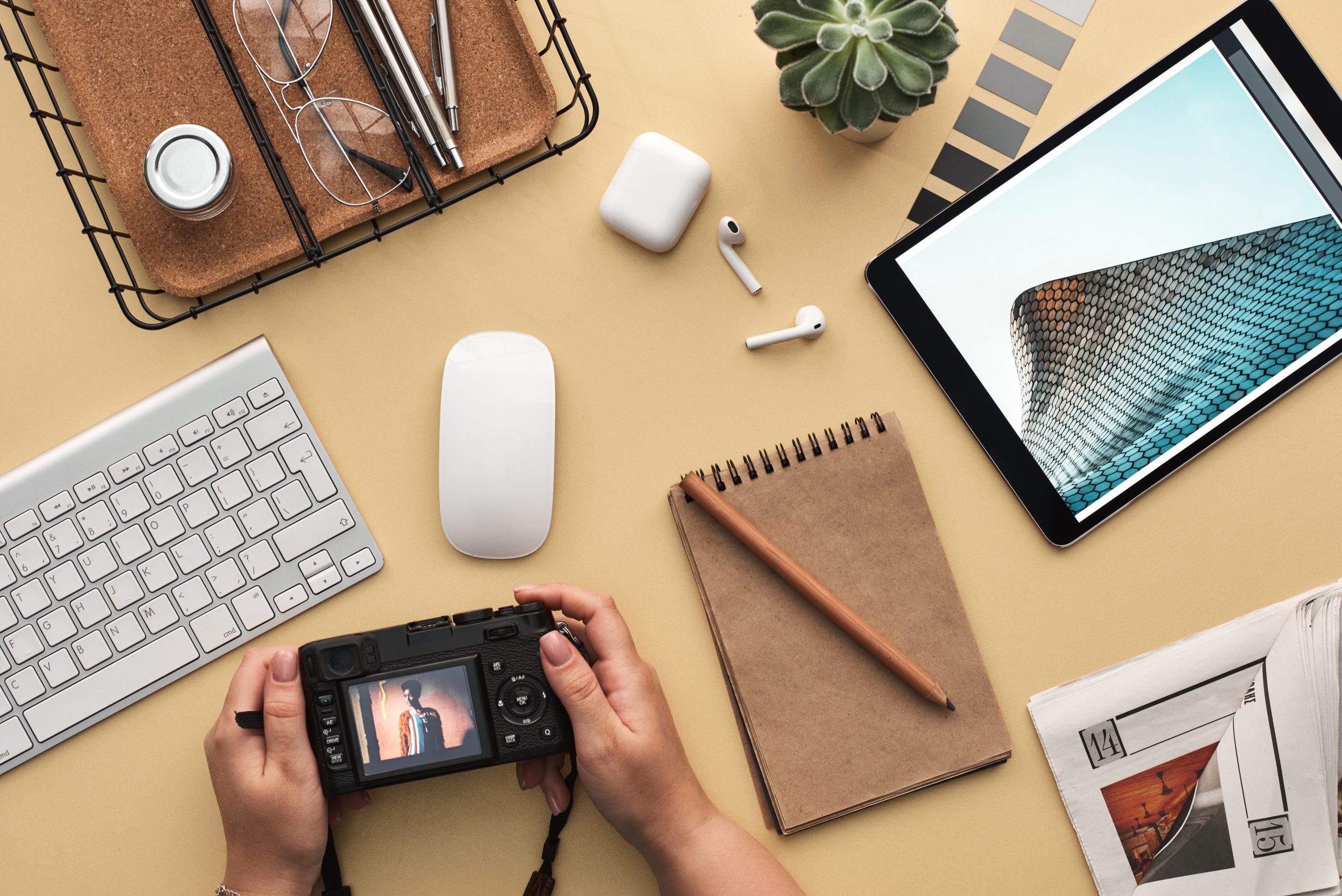 desk setup with camera, airpods, ipad, and notebook