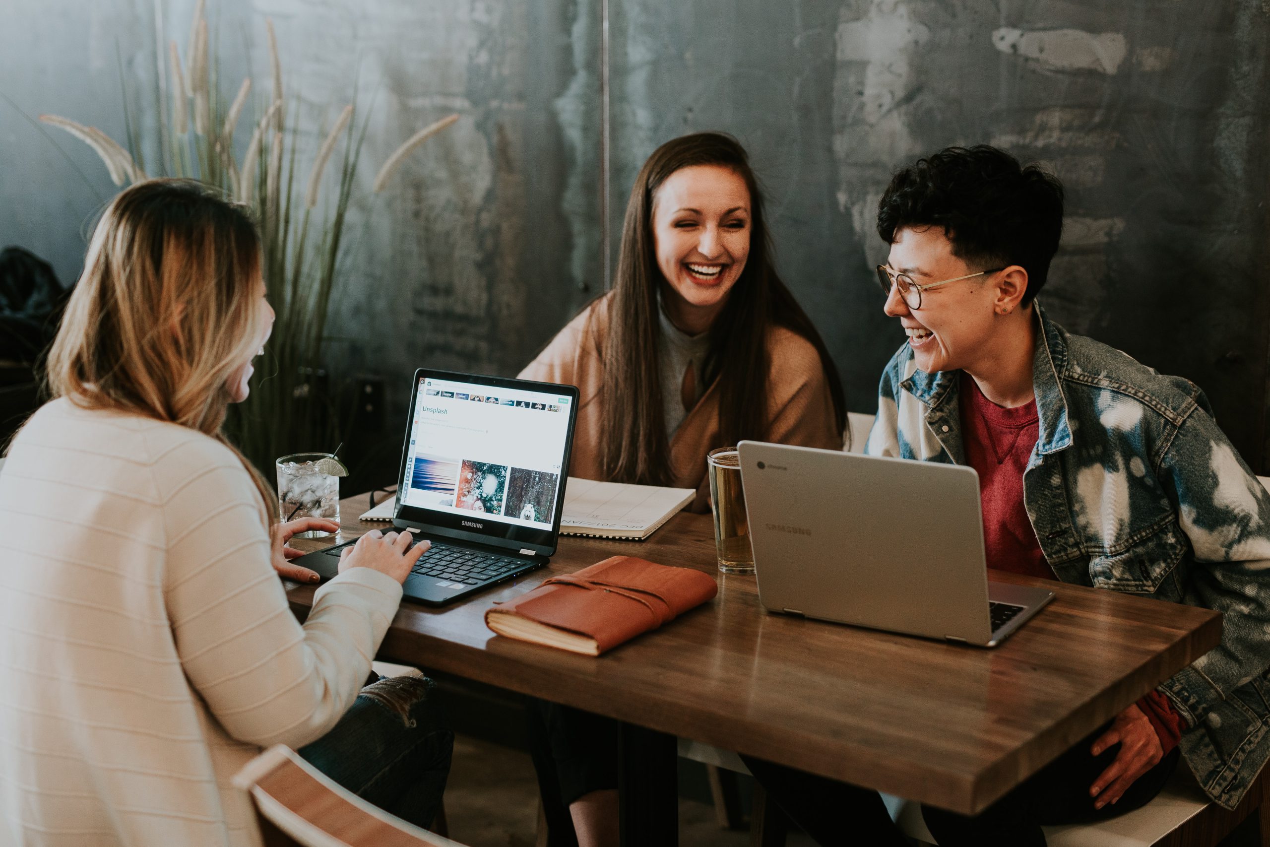 three people laughing while working around a table