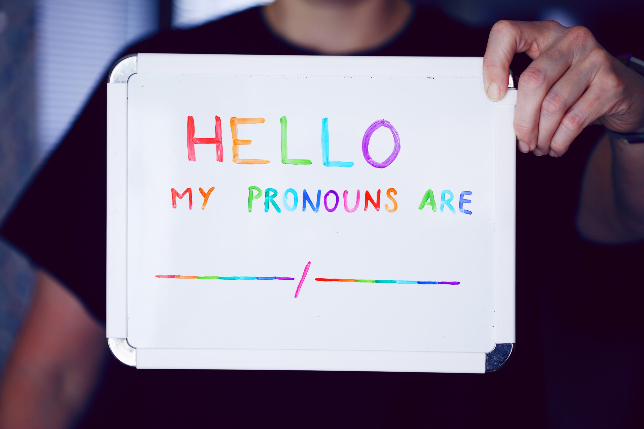 "Hello, my pronouns are..." written on a whiteboard