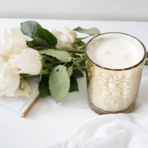 a candle on a white tablecloth with white flowers beside it