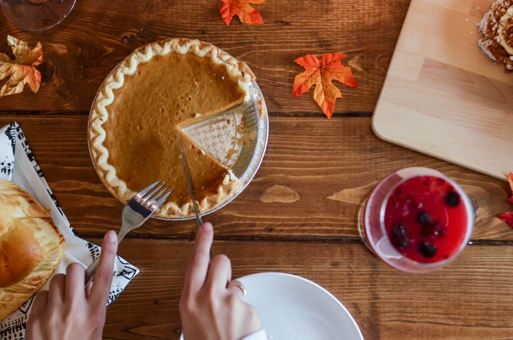 hands cutting a slice of pumpkin pie